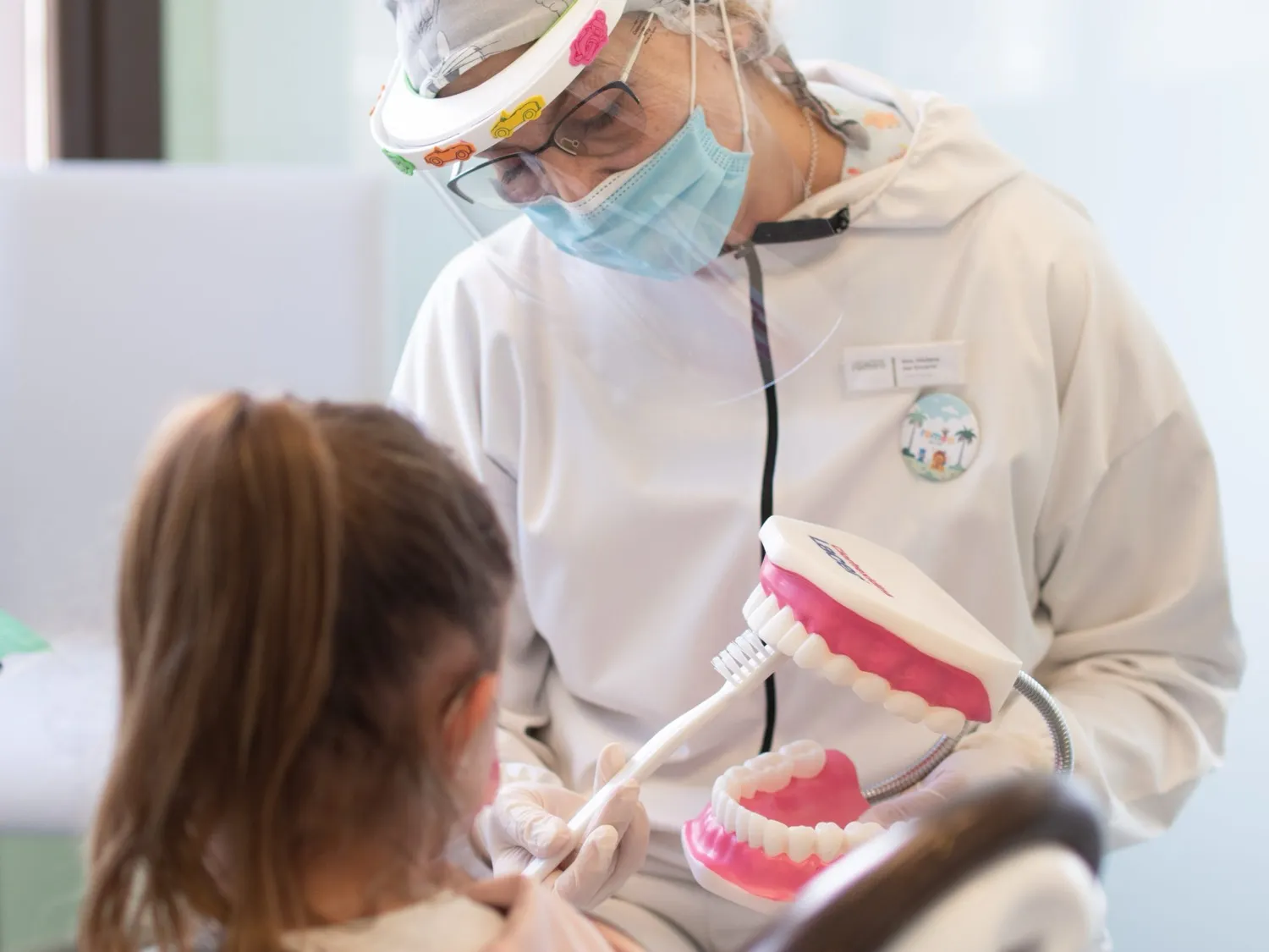 Profesional de Clínica Dental Romeo enseñando el cepillado a una niña con una maqueta dental