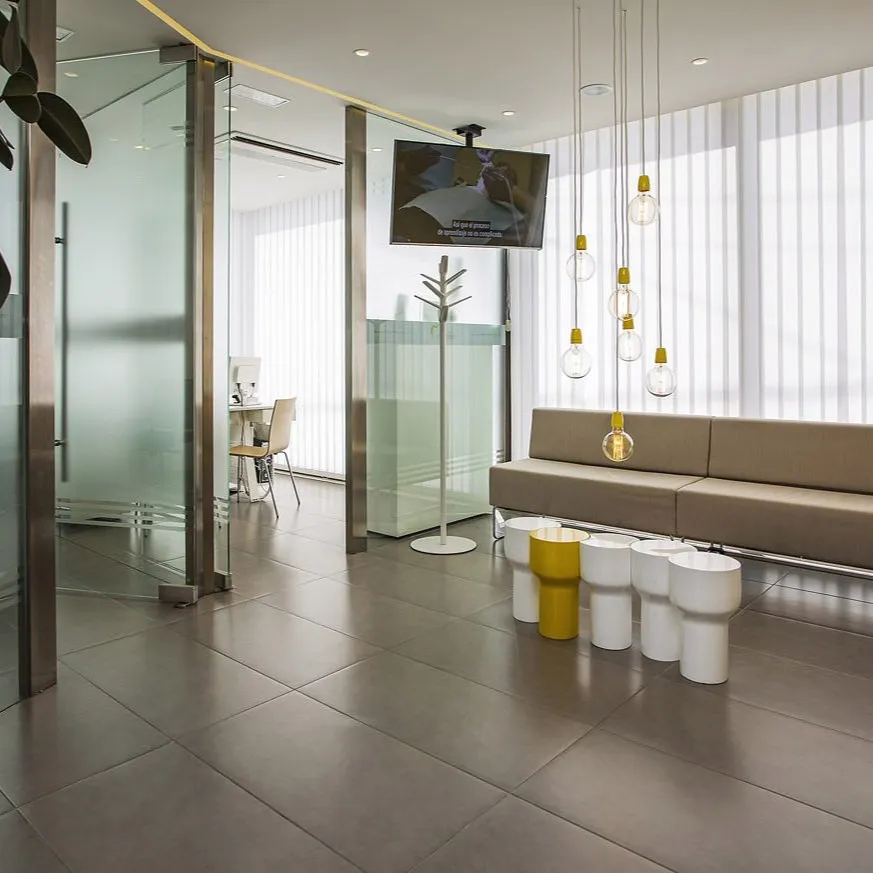 Sala de espera moderna de Clínica Dental Romeo con sofá y plantas